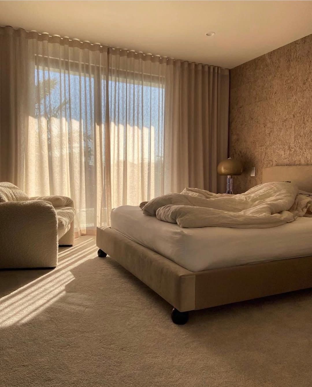 minimal IKEA bed with black legs in a warm neutral bedroom with natural light