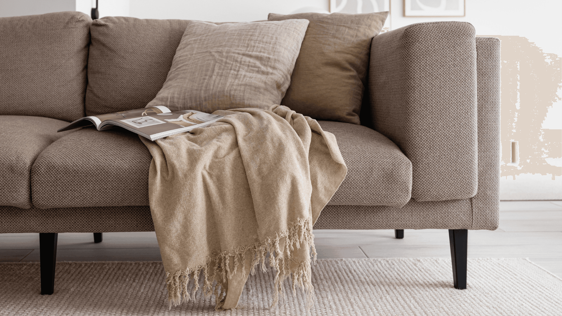 Cozy neutral living room with textured beige sofa and throw blanket on black furniture legs