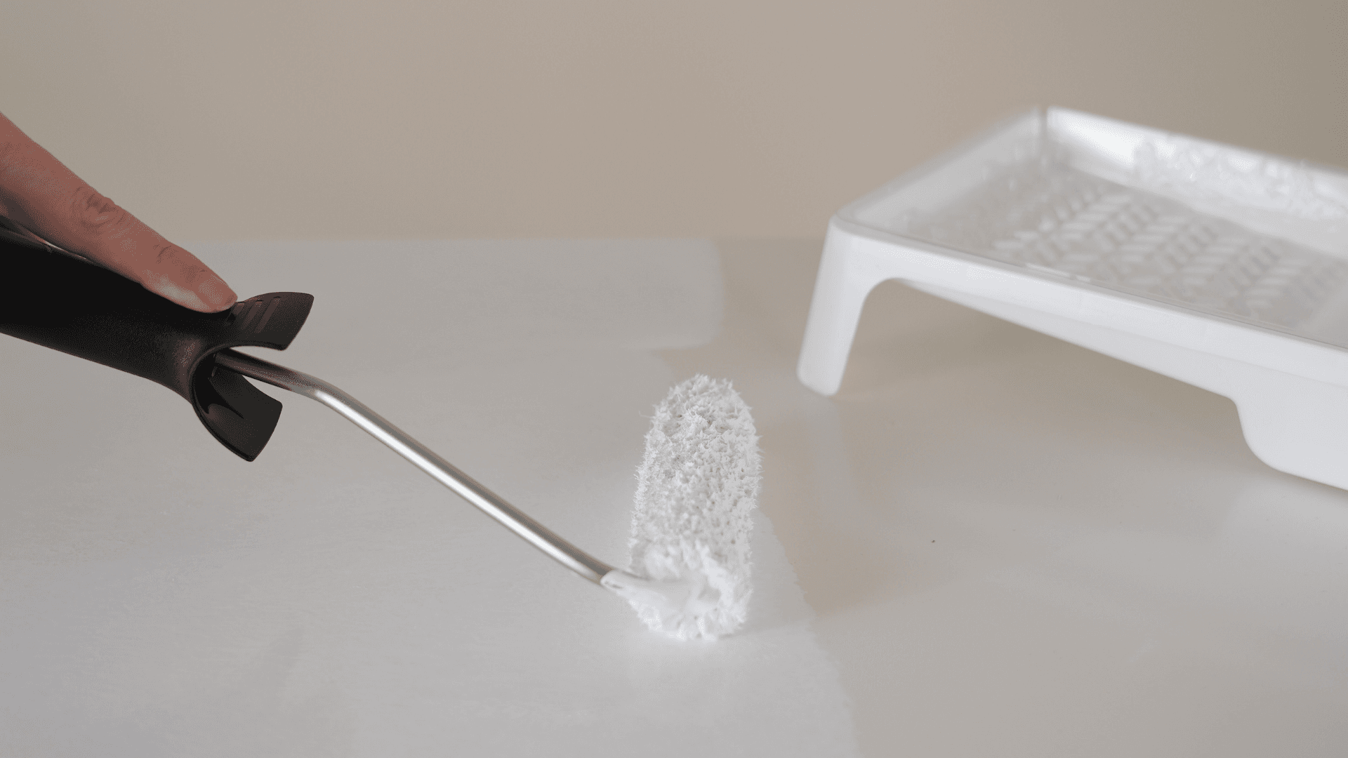 Applying white paint on furniture surface with a small roller before makeover – DIY furniture refresh