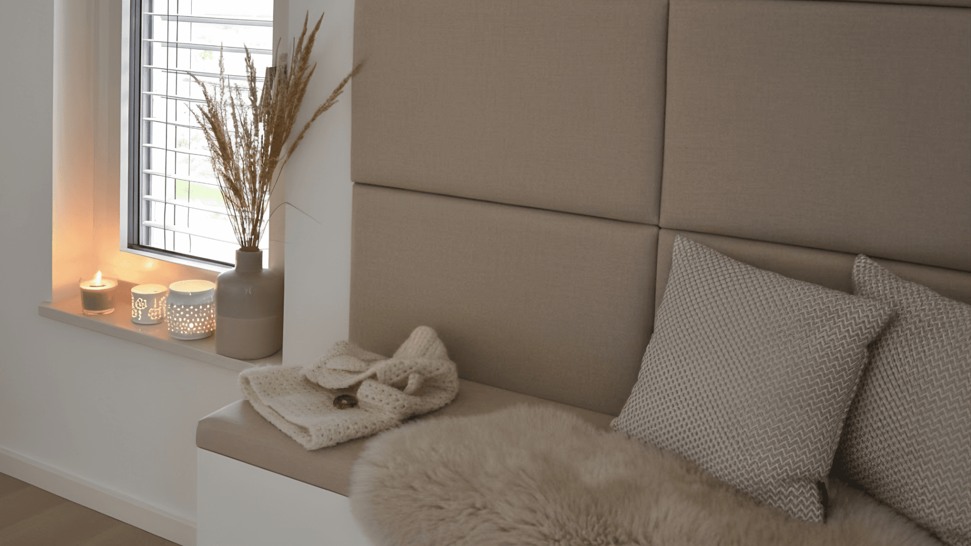 Mysig skandinavisk fönsterhörna med varmt ljus, mjuka textilier och avskalad juldekoration.